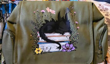 Illustration of a dragon sleeping on books with flowers around, printed on a backpack. Ideal for whimsical and fantasy-themed shopping