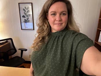 Person successful a location bureau with agelong hair, wearing a patterned blouse, smiles for a selfie
