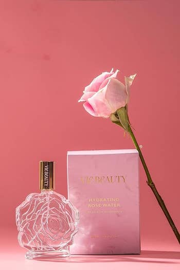 The bottle, box, and a rose with a pink background