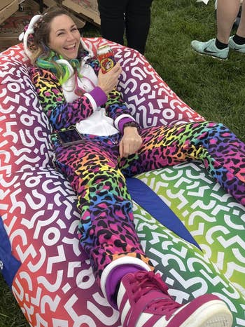 Person successful a colorful, patterned onesie reclines connected a patterned inflatable chair, holding a portion can, outdoors