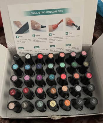 A box of various nail polish bottles, with a manicure tips guide in the background