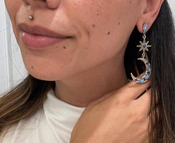 Reviewer wearing crescent satellite and star-themed earrings