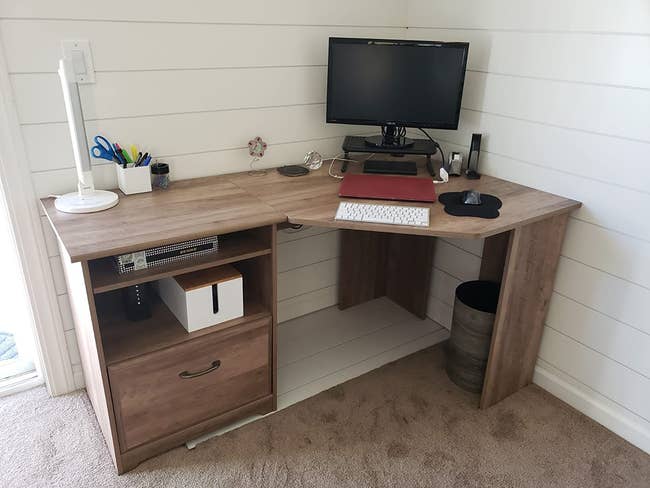 reviewer photo of a brown wooden l-shaped desk in a corner 