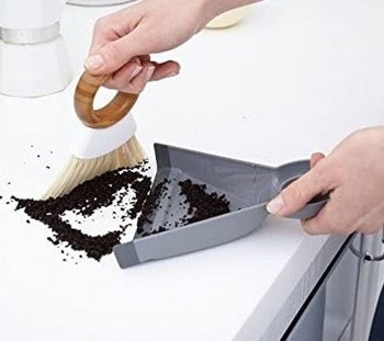 a model brushing dirt on a countertop into the mini dust pan 