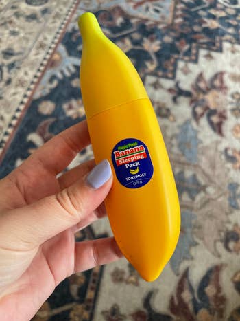 a buzzfeeder holding the banana-shaped moisturizer