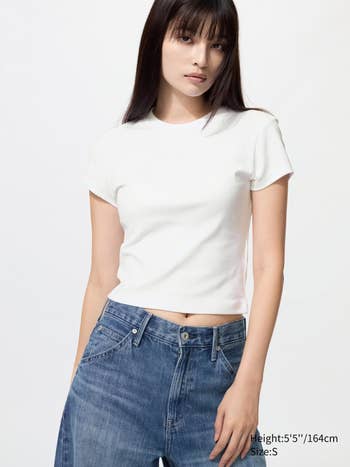Woman successful  a fitted achromatic  T-shirt and high-waisted jeans poses confidently, with substance   noting tallness  arsenic  5'5