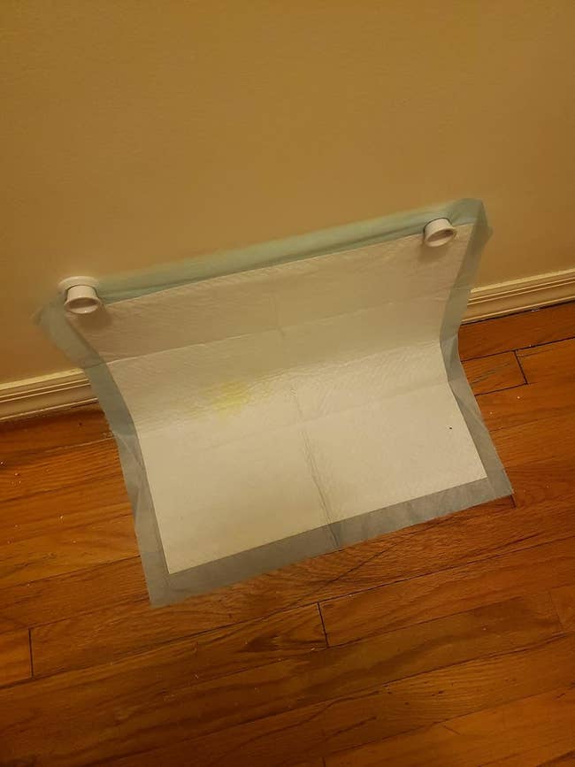 Puppy training pad on the floor with a wet spot, used for pet housebreaking