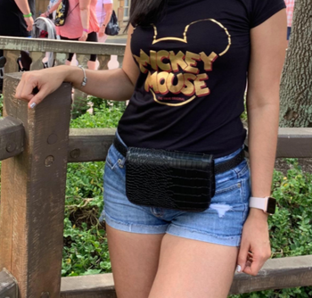 reviewer wearing the waist bag at a Disney park 