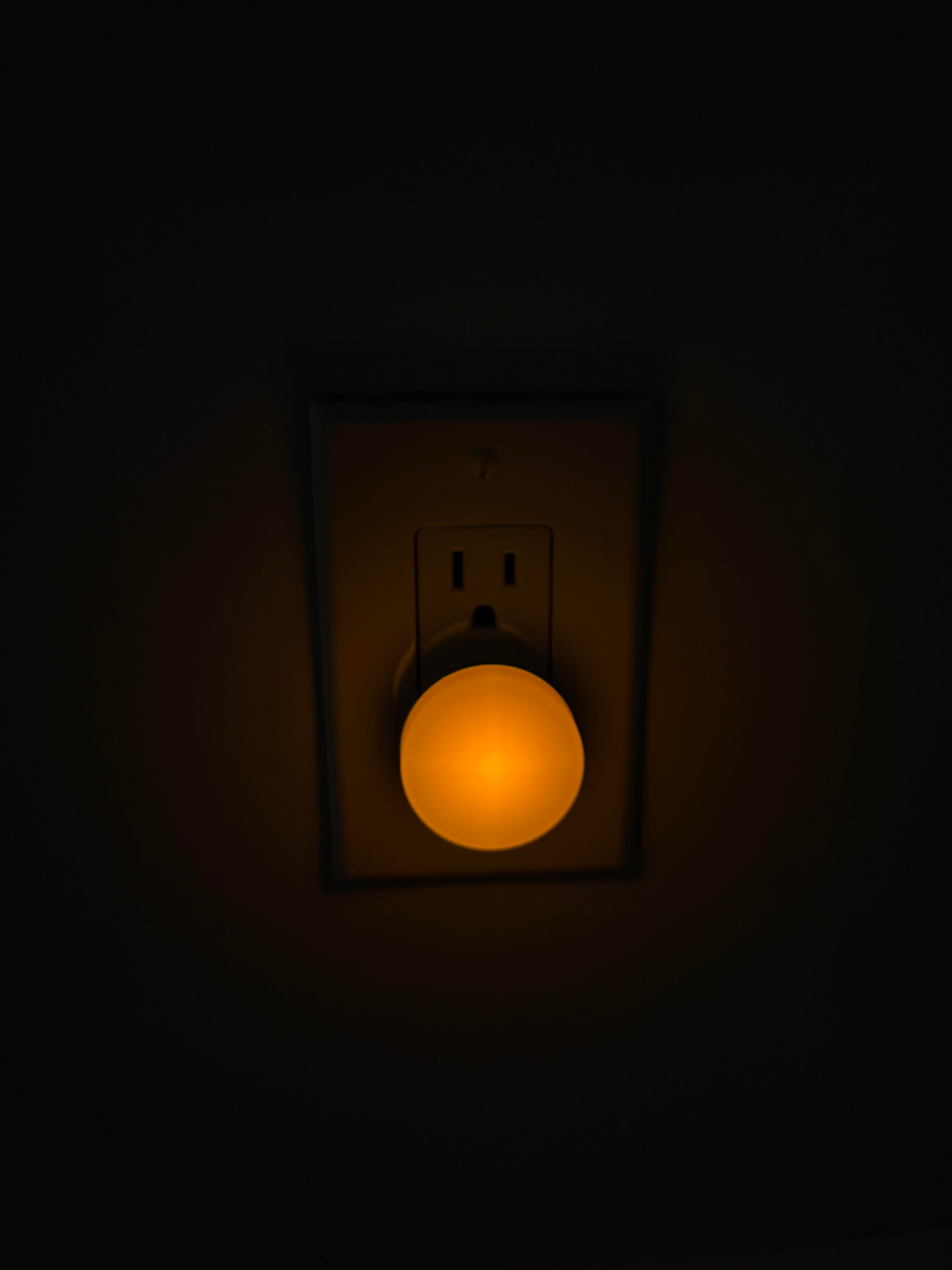 Illuminated circular  nighttime  airy  plugged into a partition  outlet, casting a brushed  glow successful  the dark