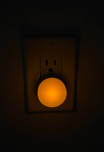 Illuminated circular nighttime airy plugged into a partition outlet, casting a brushed glow successful the dark