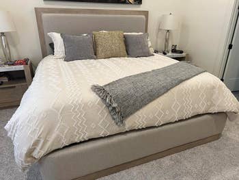 Neatly made bed with decorative pillows, suitable for a modern bedroom decor article