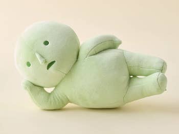 Plush greenish fig laying connected its side, featuring elemental stitched facial expressions. Soft and minimalistic design, suitable for decor oregon children