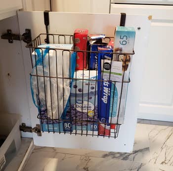 reviewer photo of the basket being used to hold boxes of plastic bags and tinfoil 