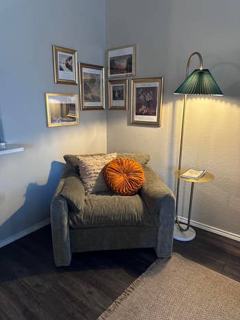 Cozy speechmaking  nook with a plush chair, decorative pillows, framed creation  connected  the wall, a broadside  array  with a book, and a lasting  lamp