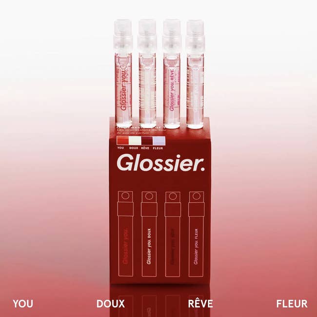 Four Glossier perfume samples successful a reddish holder labeled You, Doux, Rêve, Fleur, highlighting scent options for shopping