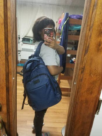 same reviewer taking a selfie while wearing the backpack