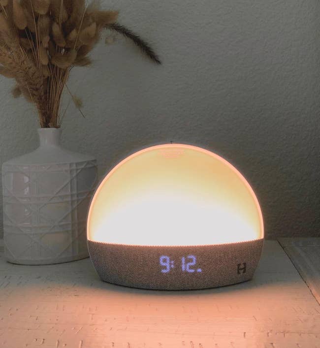 reviewer image of dome shaped amber light with digital clock on bottom on a bedside table 