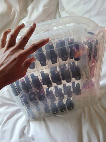 A reviewer's hand holding their shut clear polish organizer, full of their polishes