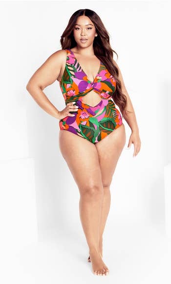 A model poses in a tropical print cutout one-piece swimsuit 