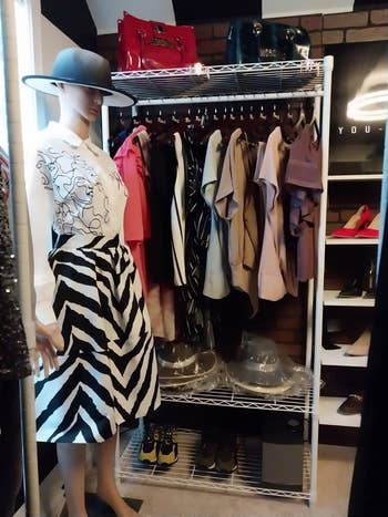 Mannequin in a boutique wearing a hat, striped skirt, and graphic tee, with racks of clothes and accessories