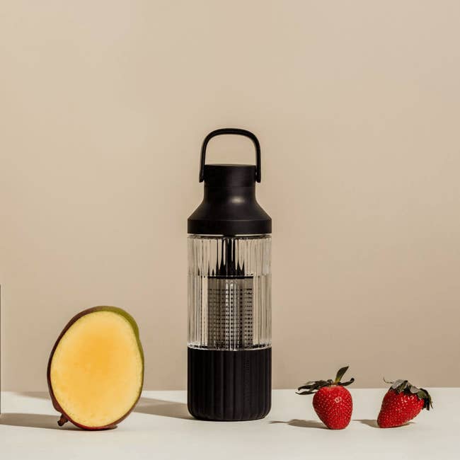 the black Beast hydration bottle with mango and strawberries next to it