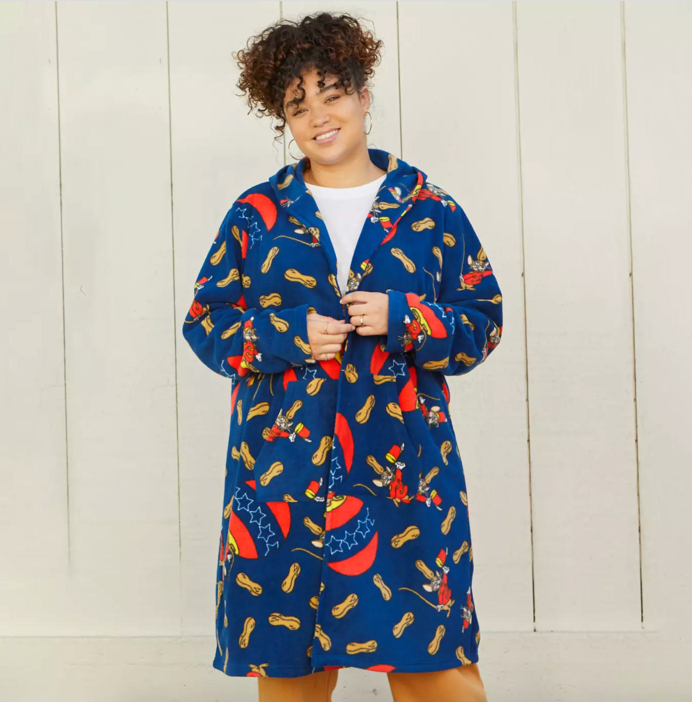 a model in a long blue fleece hooded jacket with a pattern of peanuts and timothy from dumbo on it