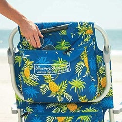 hand storing things in the back pocket of the pineapple-printed beach chair