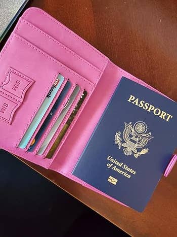Open passport holder with a U.S. passport and respective recognition cards inside, placed connected a woody surface