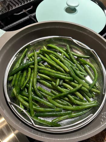 Green beans successful  a steaming handbasket  connected  a stove, acceptable   for cooking, suggest   a caller  and steadfast   cooking option
