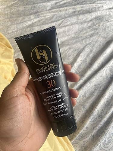 Hand holding Black Girl Sunscreen SPF 30 tube, a moisturizing lotion for look and body