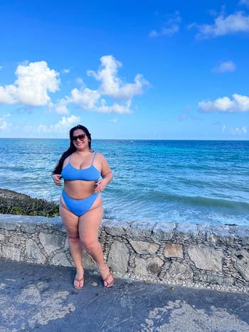 reviewer posing by the beach in blue bikini