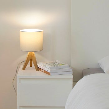 wooden tripod lamp on bedside table