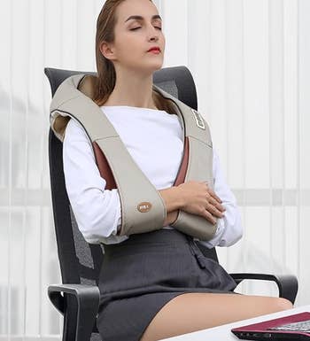 Model in office chair using a beige shoulder massage device