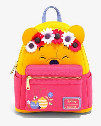 pink and yellow backpack that looks like pooh wearing a flower crown