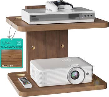 Floating TV support with a media player, remote, projector, and gaming controller displayed for a buying article