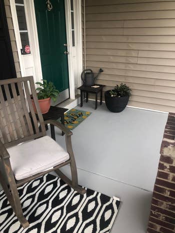 Front structure  with a woody  chair, potted plants, a doormat, and a watering tin  connected  a broadside  table
