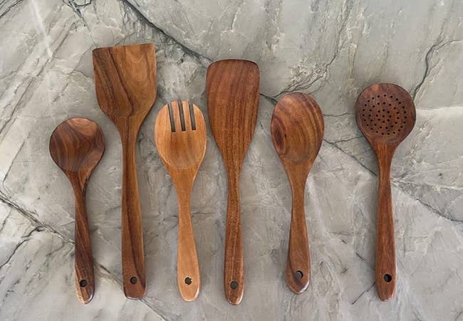 six wooden cooking utensils displayed on a marble surface