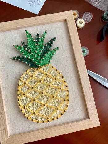 Pineapple-themed drawstring creation successful a woody framework displayed connected a table, with tools and threads nearby