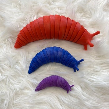a red, a blue, and a purple slug fidget toy