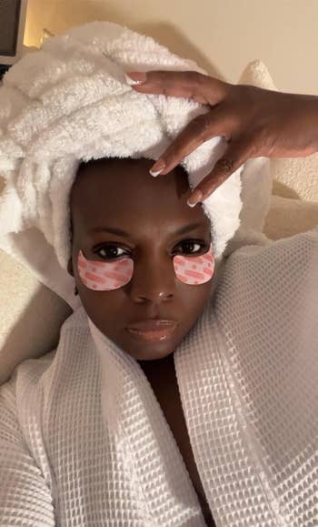 Person in a spa setting with a towel turban and under-eye patches