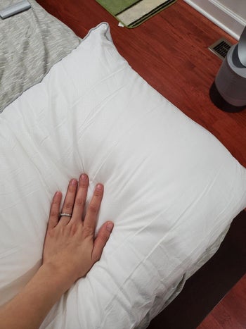 Closeup of reviewer pressing into the pillow to show its plumpness