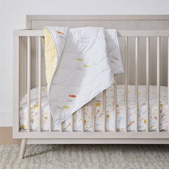 crib with sheets on and a quilt