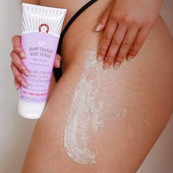 model holding bottle of scrub an applying it to thigh