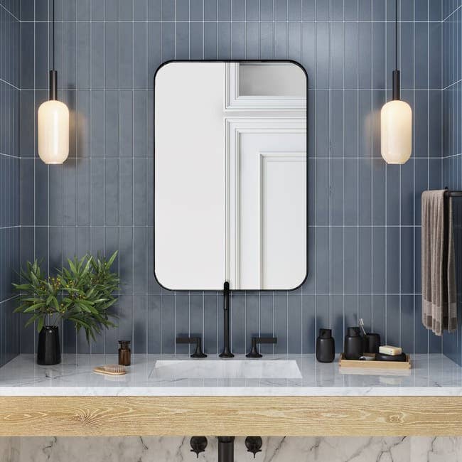 the black rectangular mirror hanging above a vanity