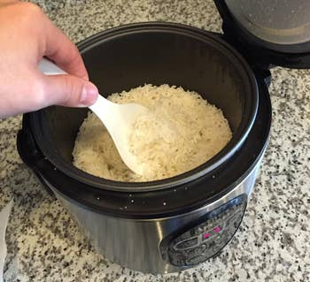 The rice cooker with cooked rice in it 
