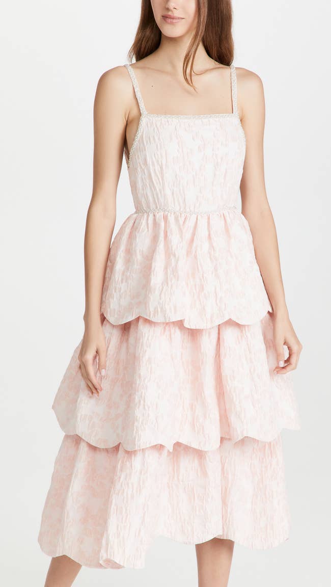 model in pale pink tiered spaghetti strap fit and flare with beading at the straps and waist