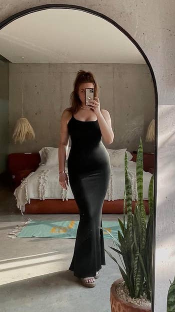 Reviewer in a black sleeveless dress posing in front of a mirror for a selfie