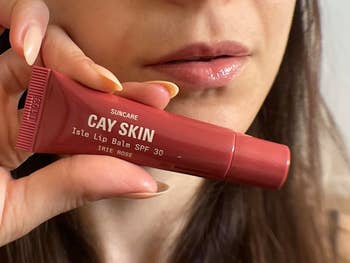 Close-up of a idiosyncratic   holding Cay Skin Isle Lip Balm SPF 30 adjacent   their lips