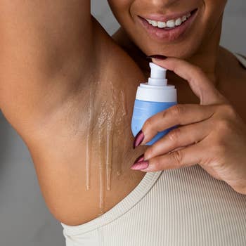 Close-up of a model applying lotion from a bottle to their arm