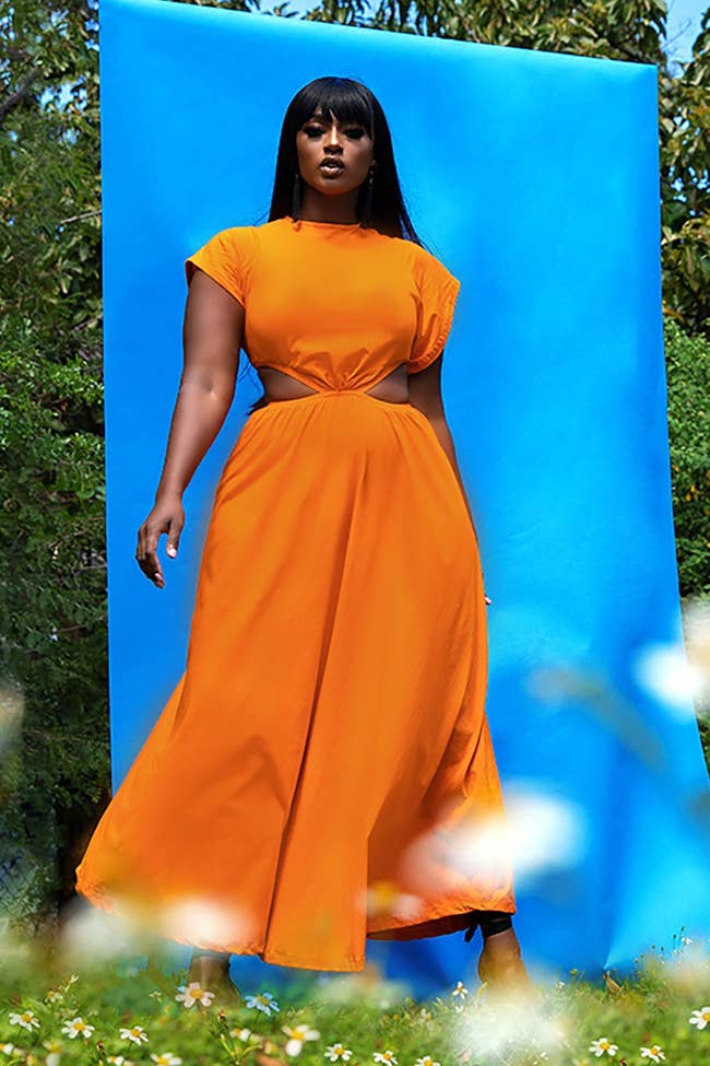 a model wearing the orange maxi dress with cut out hips